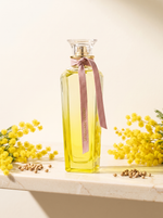 Adolfo Dominguez Agua Fresca Mimosa Coriandro 120 ml - gelber Flakon mit Band auf hellem Marmor mit Mimosen