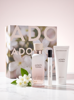 Adolfo Dominguez Jazmin Tonka Geschenkset - Flakon Reisespray und Bodylotion mit Verpackung auf hellem Marmor mit Jasmin