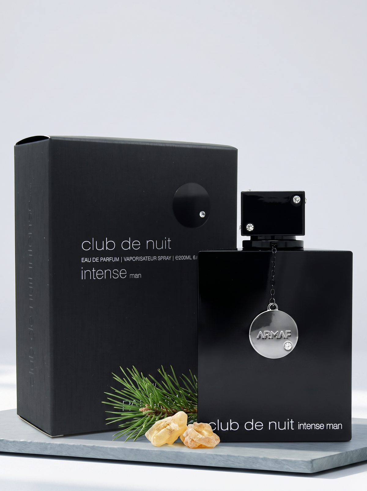 Armaf Club de Nuit Intense Man Eau de Parfum 200 ml - Flakon mit Verpackung auf hellem Schiefer mit Kiefernzweig