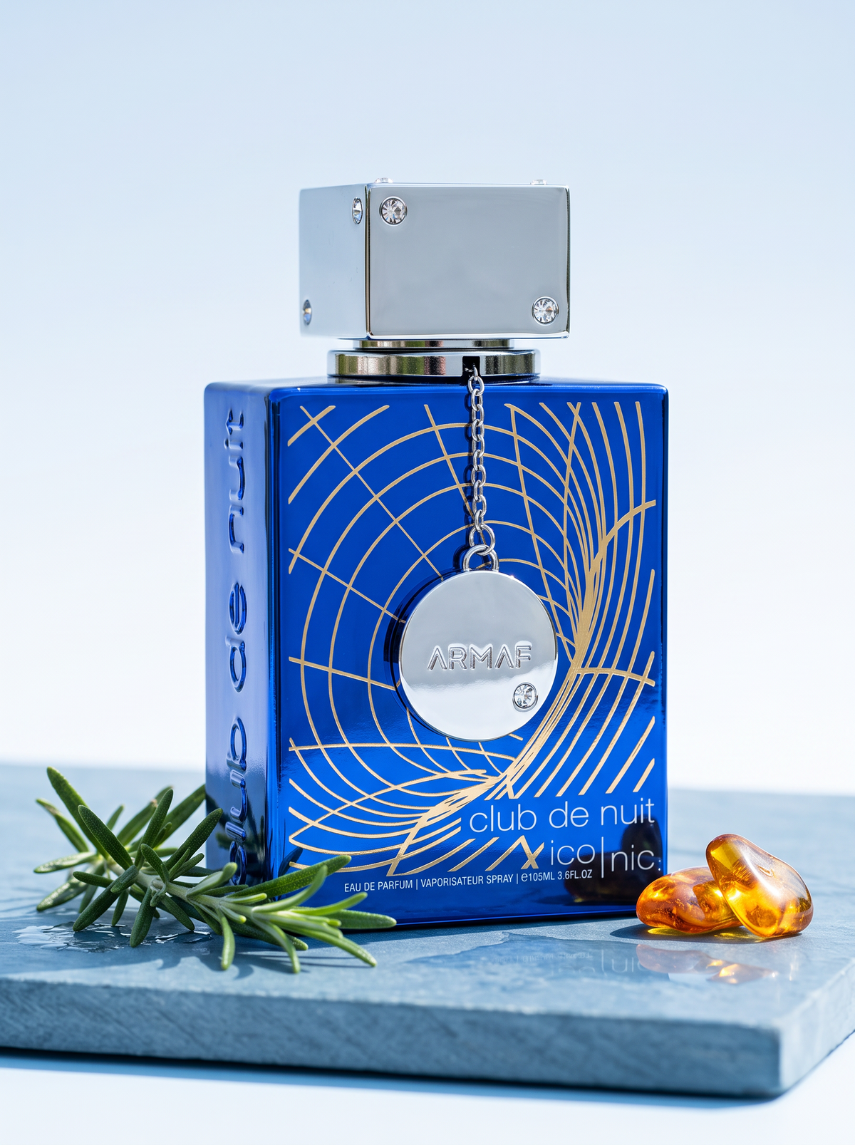 Armaf Club de Nuit Iconic Eau de Parfum 105 ml - blauer Flakon auf Schiefer mit Rosmarin und Bernstein