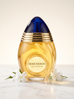 Boucheron Femme Eau de Parfum 100 ml - Eiflakon mit blauer Kuppel auf hellem Marmor mit weissen Blueten