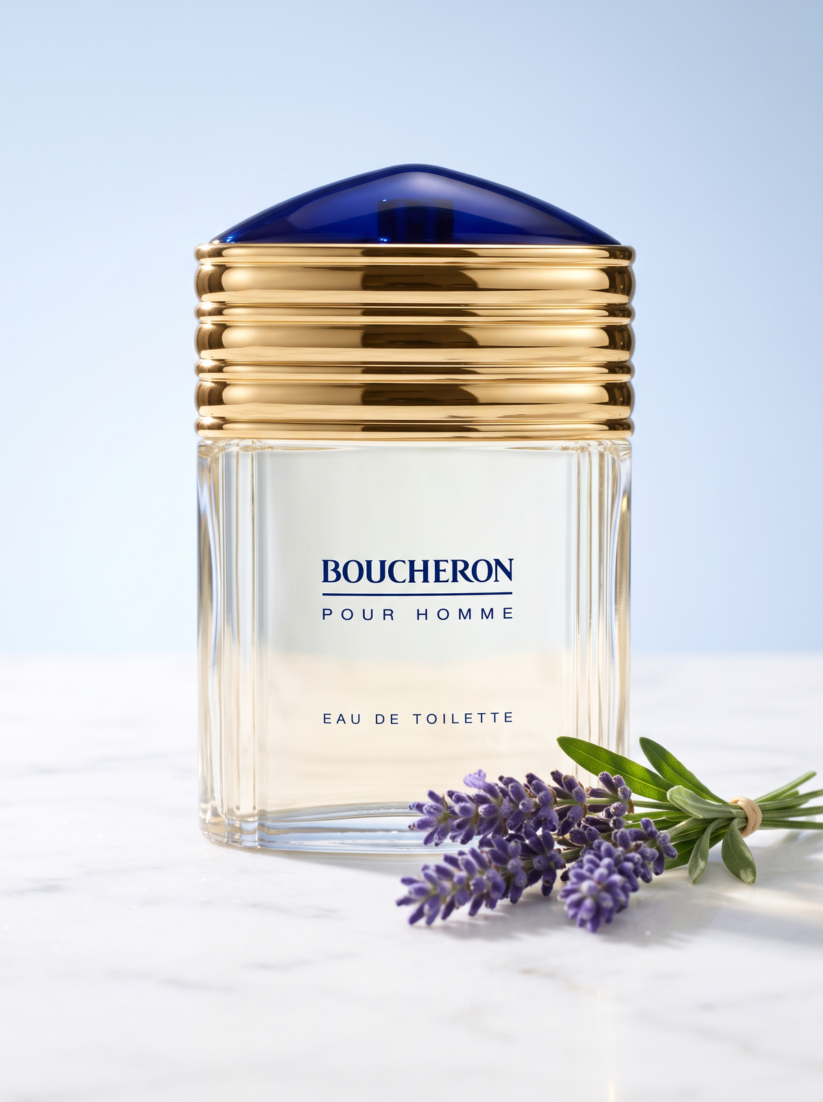Boucheron Pour Homme Eau de Toilette 100 ml - Flakon mit Goldkappe und blauer Kuppel auf hellem Marmor mit Lavendel