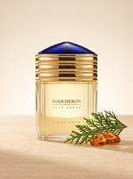 Boucheron Pour Homme Eau de Parfum 100 ml - Flakon mit Goldkappe und blauer Kuppel auf hellem Holz mit Zeder