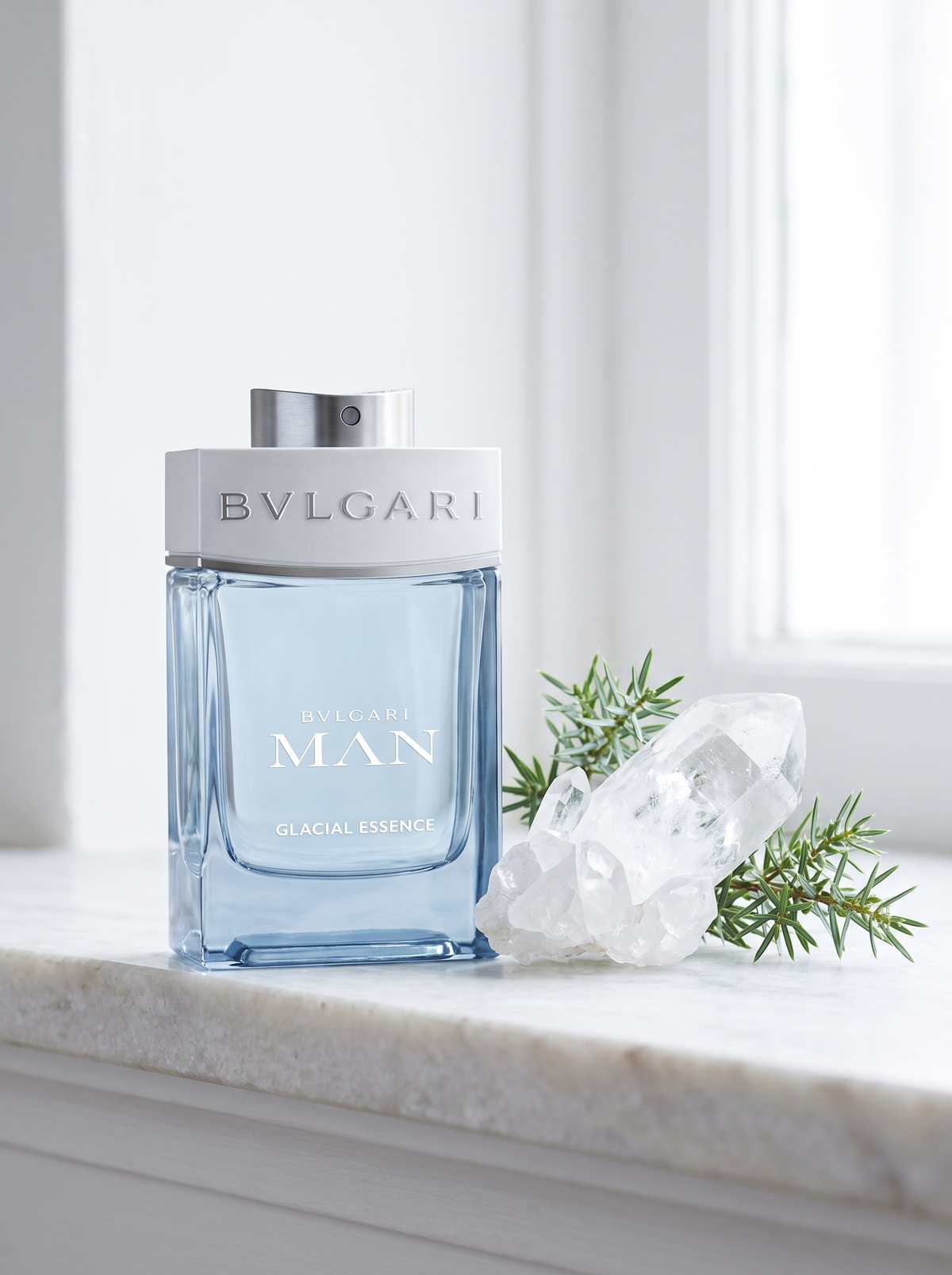 Bvlgari Man Glacial Essence Eau de Parfum 100 ml - eisblauer Flakon auf weissem Marmor mit Bergkristall und Wacholder
