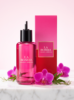 Carolina Herrera La Bomba Eau de Parfum Nachfuellung 200 ml - pinker Flakon mit Verpackung auf hellem Marmor mit Orchideen