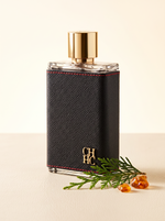 Carolina Herrera CH Men Eau de Toilette 200 ml - Flakon mit Lederhuelle auf hellem Leder mit Zedernzweig