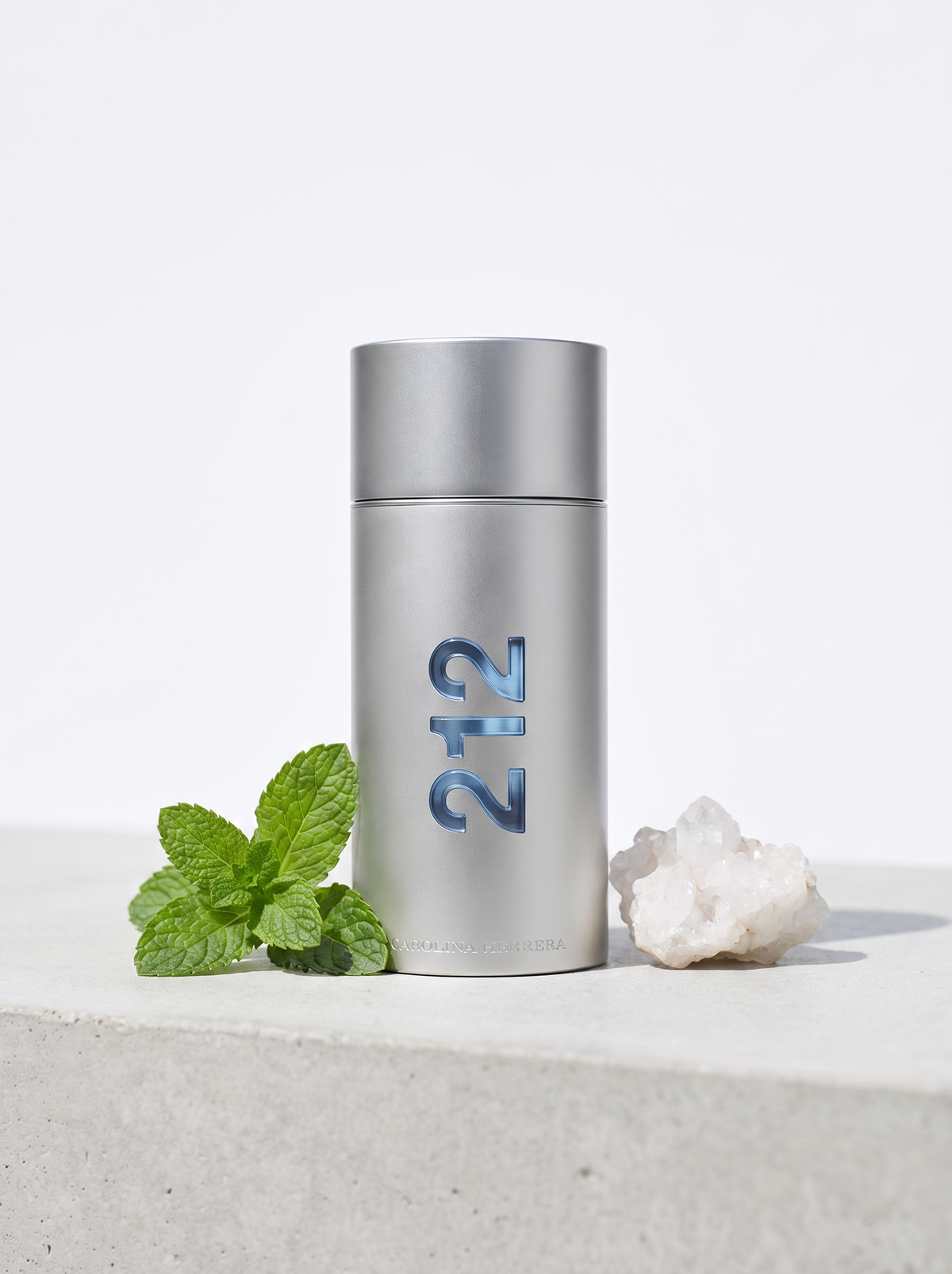 Carolina Herrera 212 Men Eau de Toilette 200 ml - silberner Flakon auf hellem Beton mit Minze