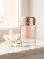 Cartier Baiser Vole Eau de Parfum 100 ml - Flakon mit Goldkappe auf hellem Marmor mit weisser Lilie