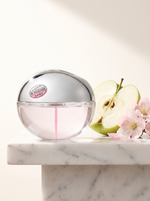 DKNY Be Extra Delicious Eau de Parfum 100 ml - Apfel-Flakon auf weissem Marmor mit Apfel und Blueten