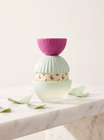 El Ganso Fun & Free Eau de Parfum 100 ml - pastellfarbener Flakon auf weissem Marmor mit gruenen Blaettern