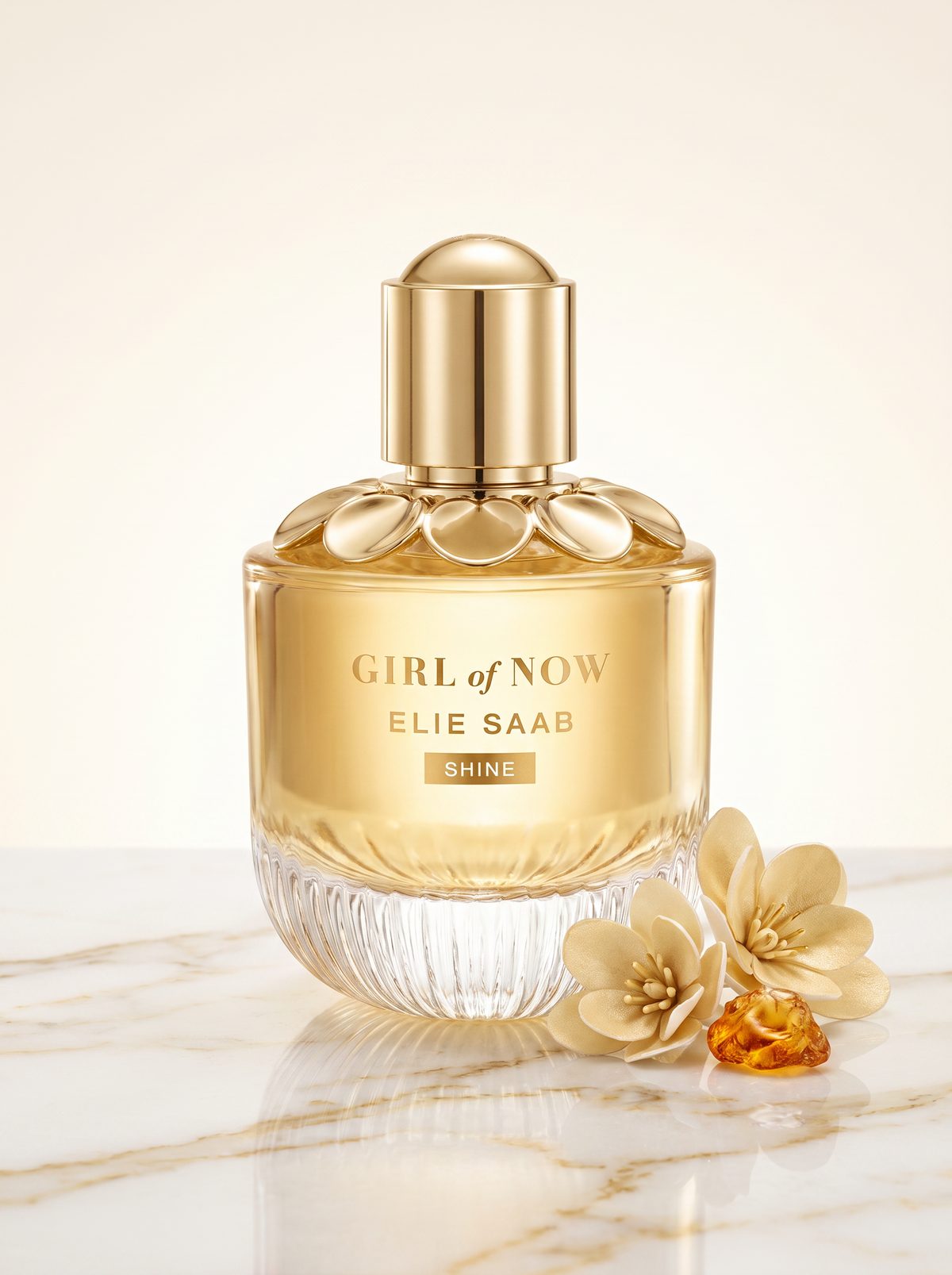 Elie Saab Girl of Now Shine Eau de Parfum 30 ml - goldener Flakon auf hellem Marmor mit cremefarbenen Blueten