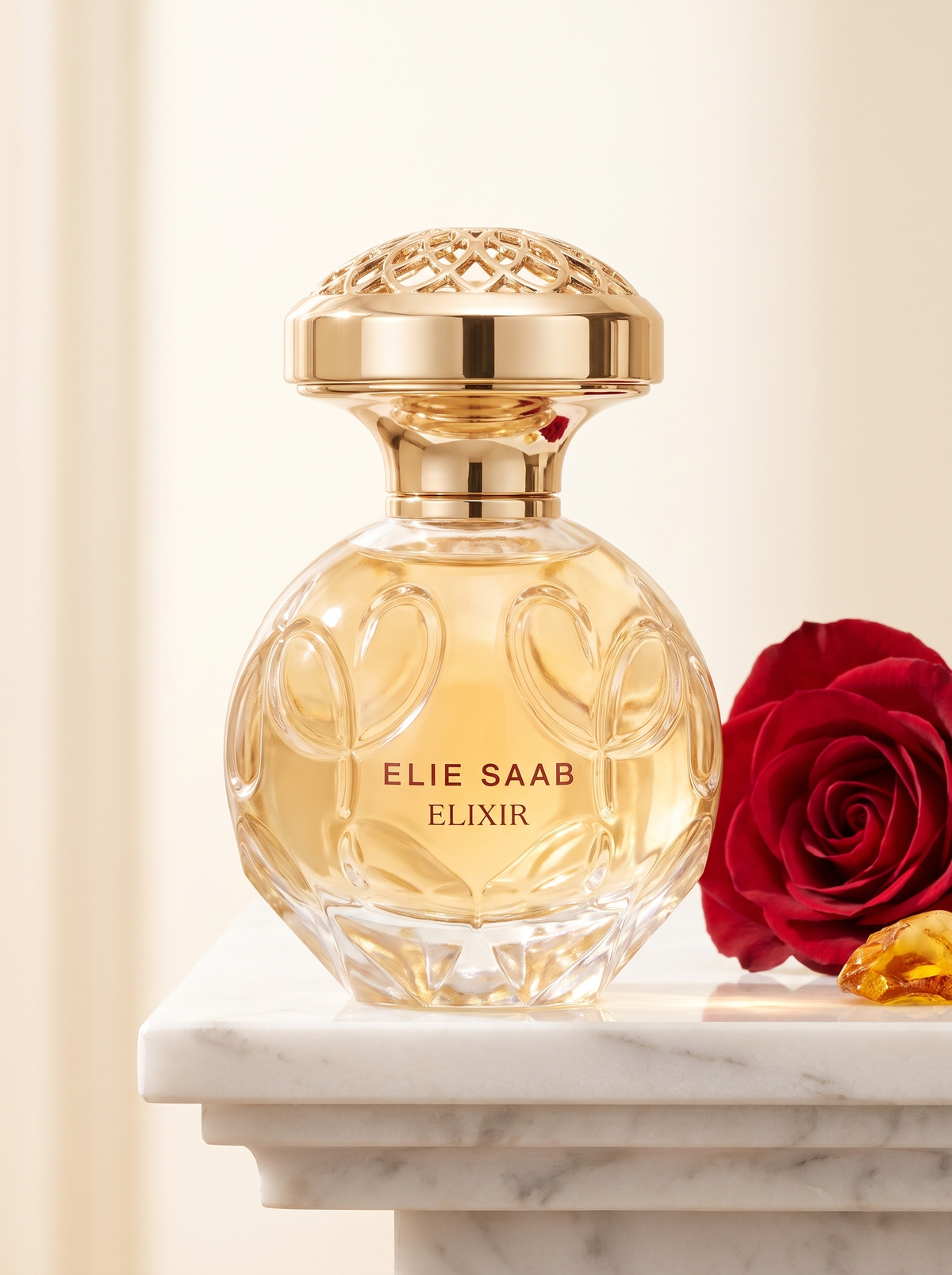 Elie Saab Elixir Eau de Parfum 50 ml - goldener Flakon auf weissem Marmor mit roter Rose