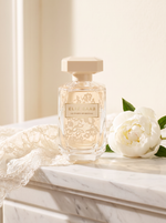 Elie Saab Le Parfum Bridal Eau de Parfum 90 ml - cremefarbener Flakon auf weissem Marmor mit Spitze und Pfingstrose