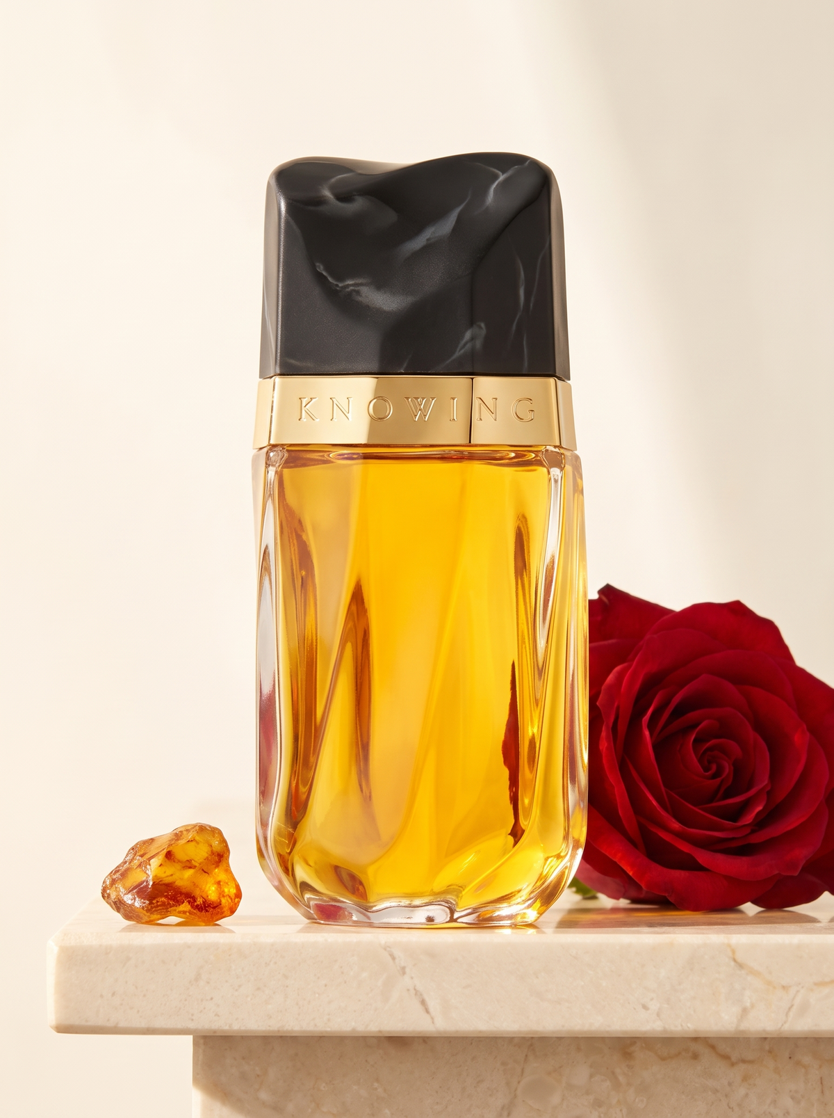 Estee Lauder Knowing Eau de Parfum 75 ml - Flakon mit Goldband auf hellem Marmor mit roter Rose