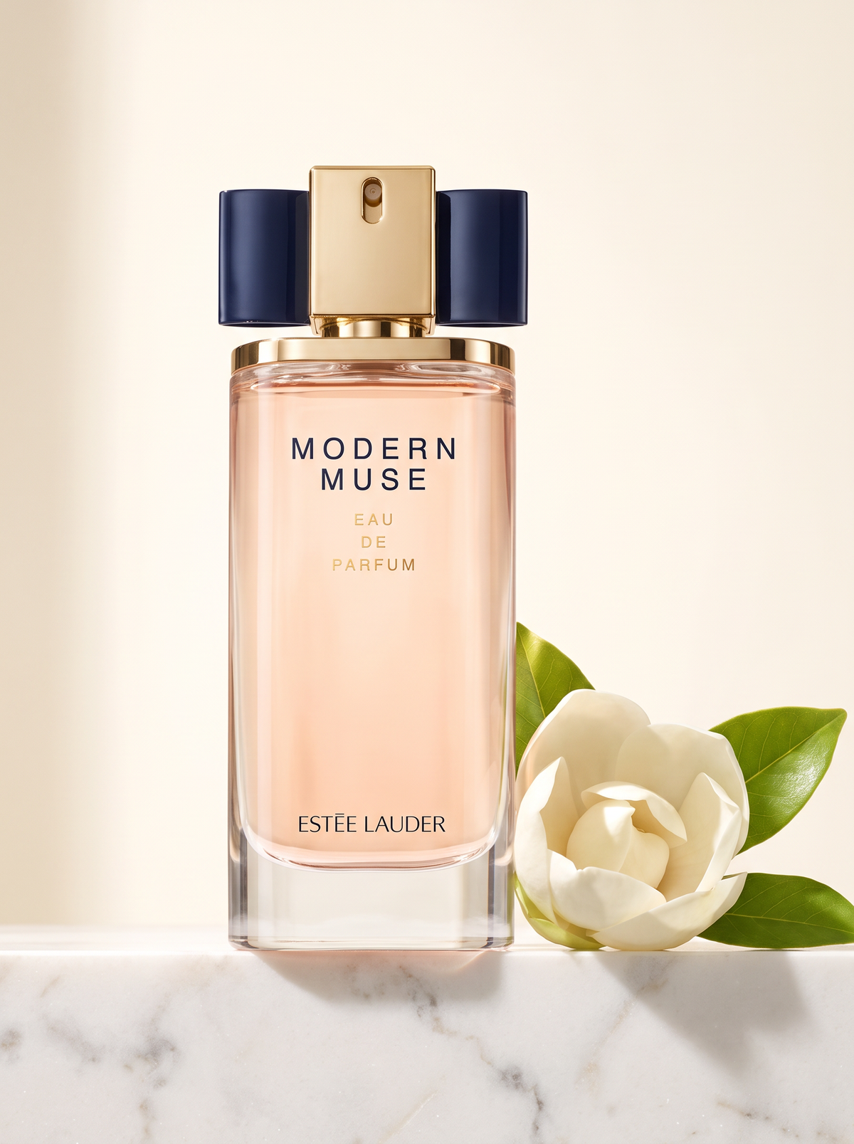 Estee Lauder Modern Muse Eau de Parfum 50 ml - Flakon mit blauer Schleife auf weissem Marmor mit Magnolie