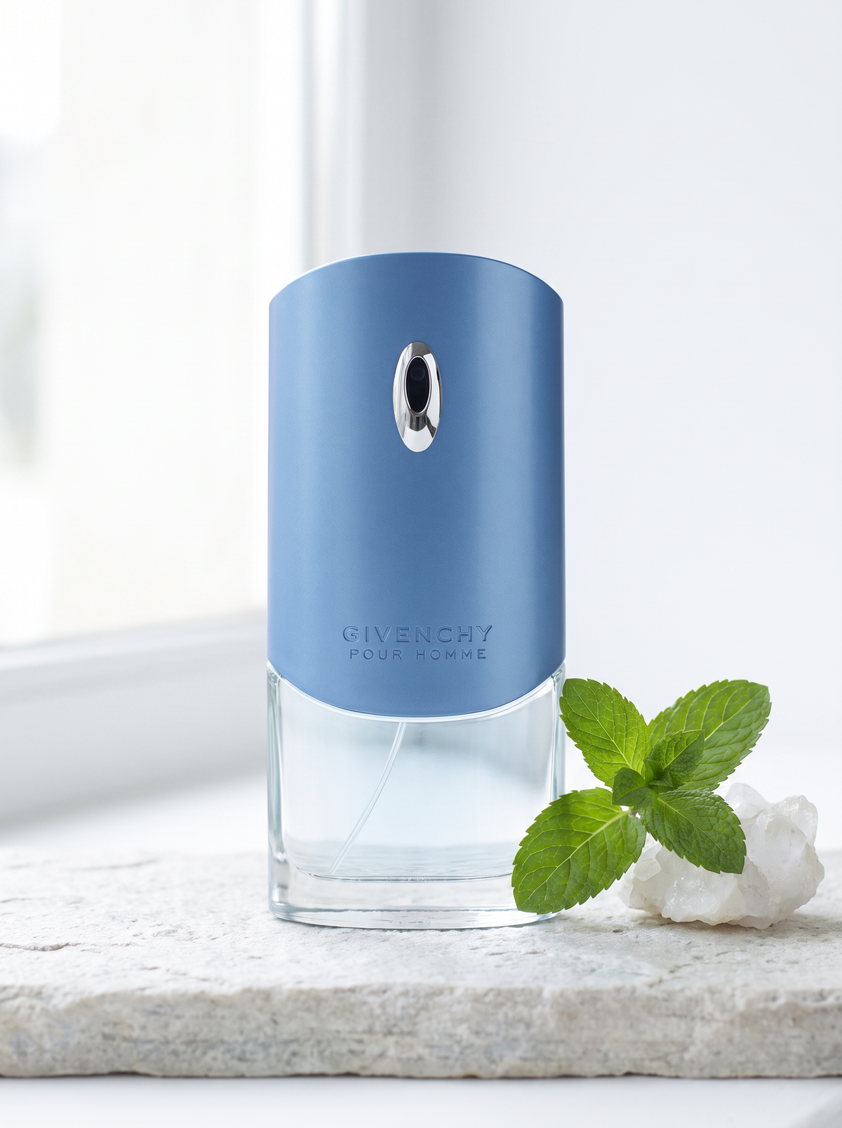 Givenchy pour Homme Blue Label Eau de Toilette 100 ml - blauer Flakon auf hellem Stein mit Minze