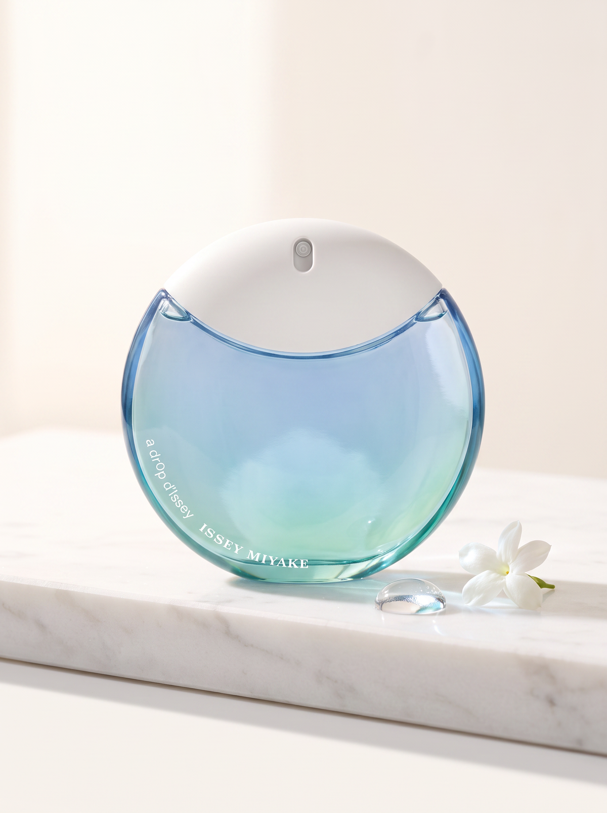 Issey Miyake A Drop d'Issey Eau de Parfum 30 ml - tuerkis-blauer Tropfen-Flakon auf weissem Marmor mit Jasmin