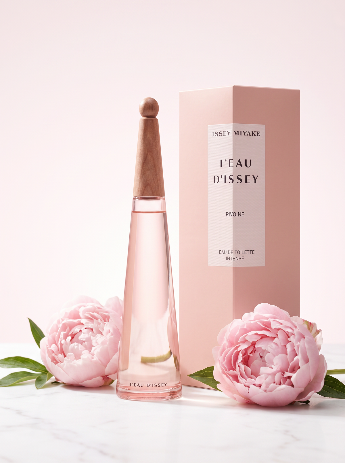 Issey Miyake L Eau d Issey Pivoine Eau de Toilette Intense 100 ml - Flakon mit Verpackung auf hellem Marmor mit Pfingstrosen