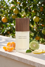 Issey Miyake L'Eau d'Issey Pour Homme EdT - Flakon mit Holzdeckel vor Zitrushain mit Mandarine, Bergamotte und Zitrone - kaufenparfum.de