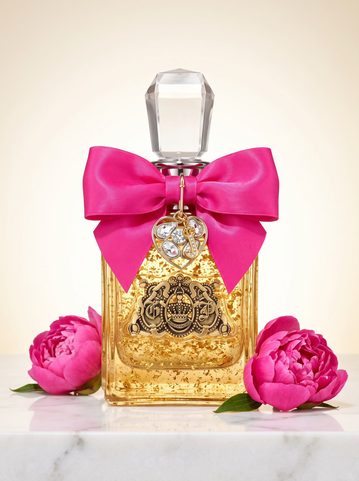 Juicy Couture Viva la Juicy Eau de Parfum 50 ml - goldener Flakon mit pinker Schleife auf hellem Marmor mit Pfingstrosen