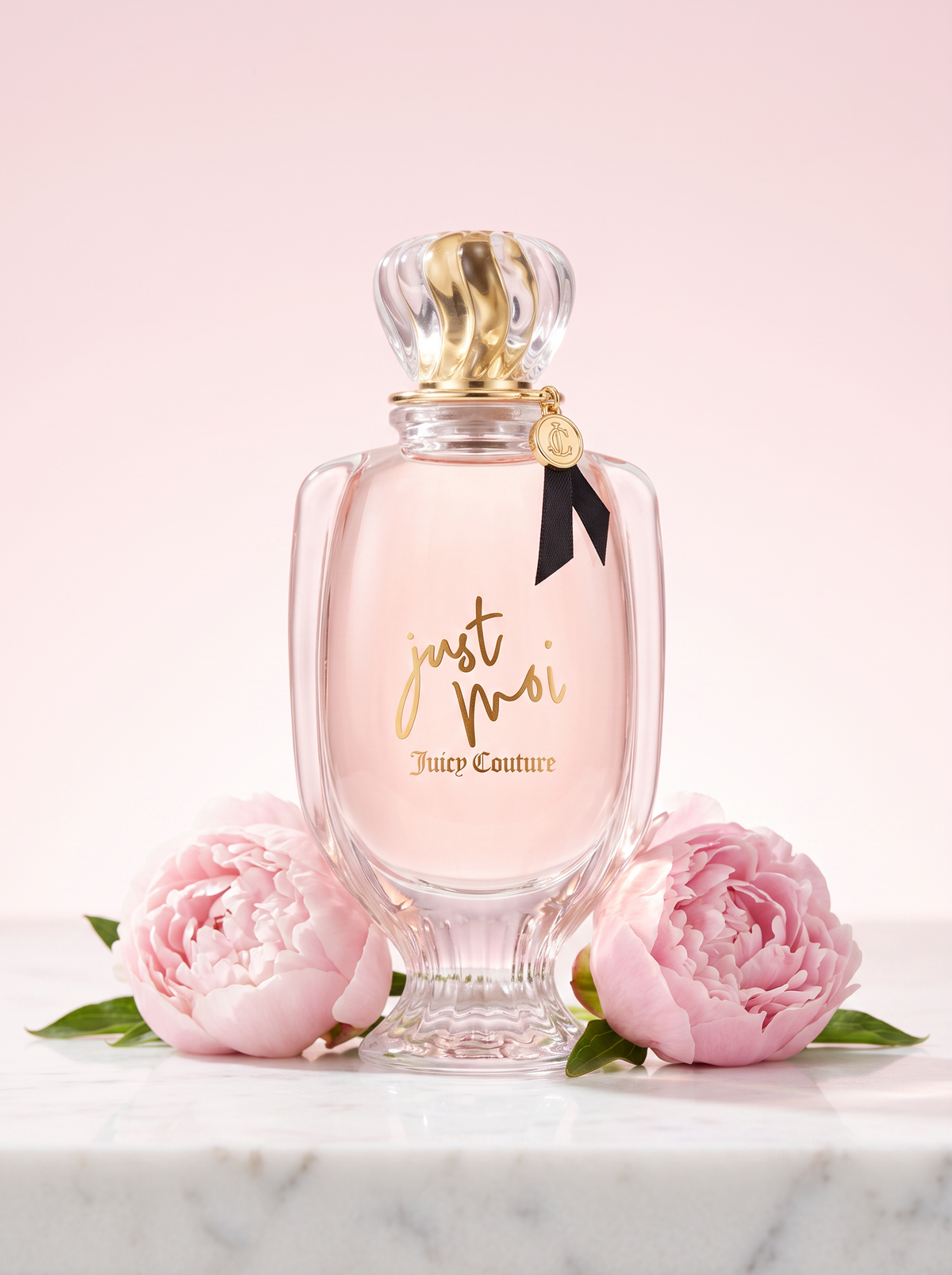 Juicy Couture Just Moi Eau de Parfum 100 ml - rosa Flakon auf hellem Marmor mit Pfingstrosen
