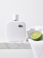 Lacoste L.12.12 Blanc Eau de Toilette 100 ml - weisser Pique-Flakon auf weissem Marmor mit Limette