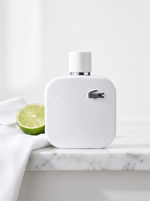 Lacoste L.12.12 Blanc Eau de Parfum 50 ml - weisser Pique-Flakon auf weissem Marmor mit Limette