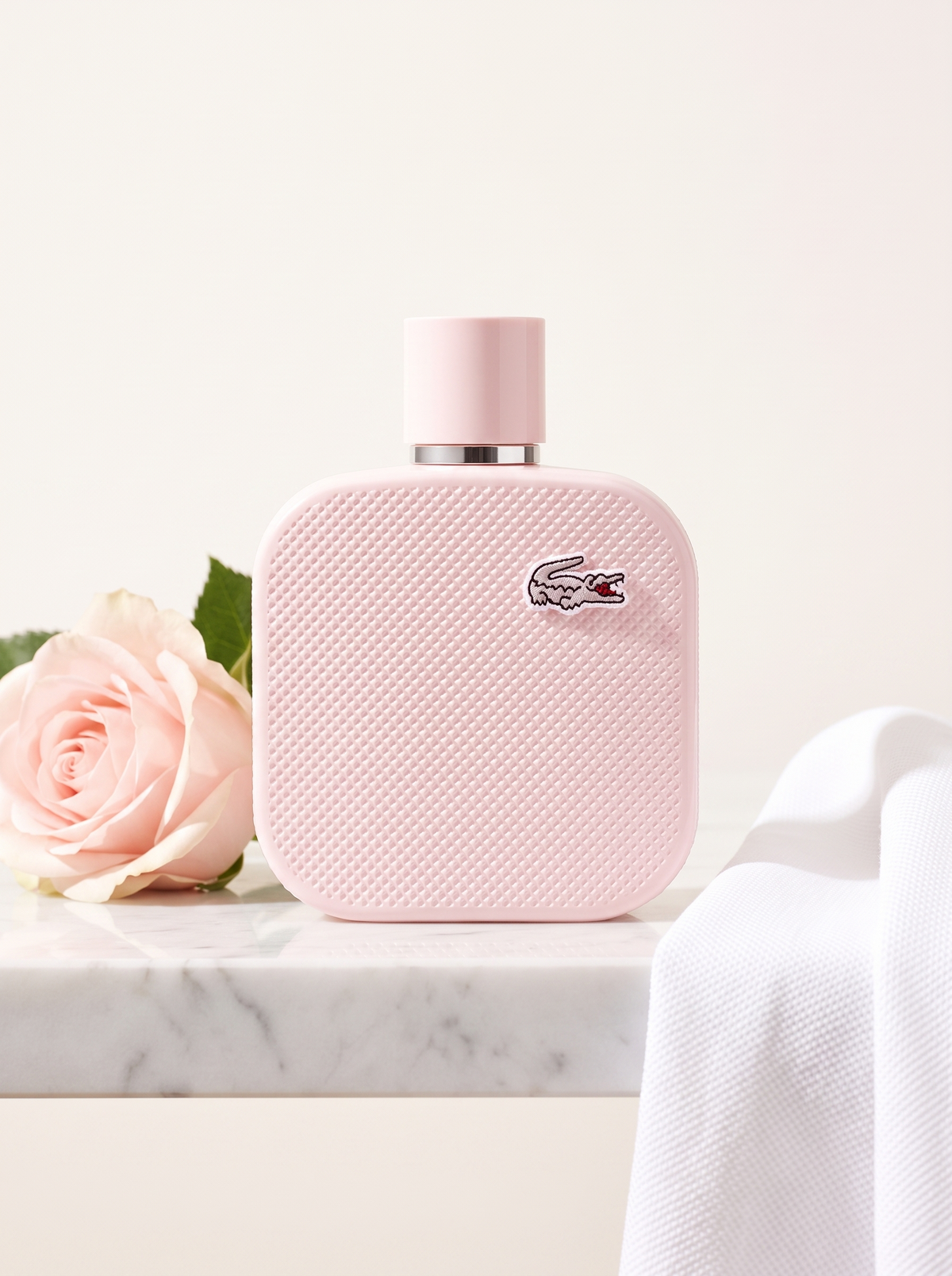 Lacoste L.12.12 Rose Eau de Parfum 100 ml - rosa Pique-Flakon auf weissem Marmor mit Rose
