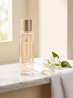 Lacoste pour Femme Eau de Parfum 50 ml - Flakon mit Goldkappe auf weissem Marmor mit Jasmin