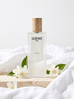 Loewe 001 Woman Eau de Parfum 75 ml - Flakon mit Holzdeckel auf hellem Stein mit Jasmin und Leinen