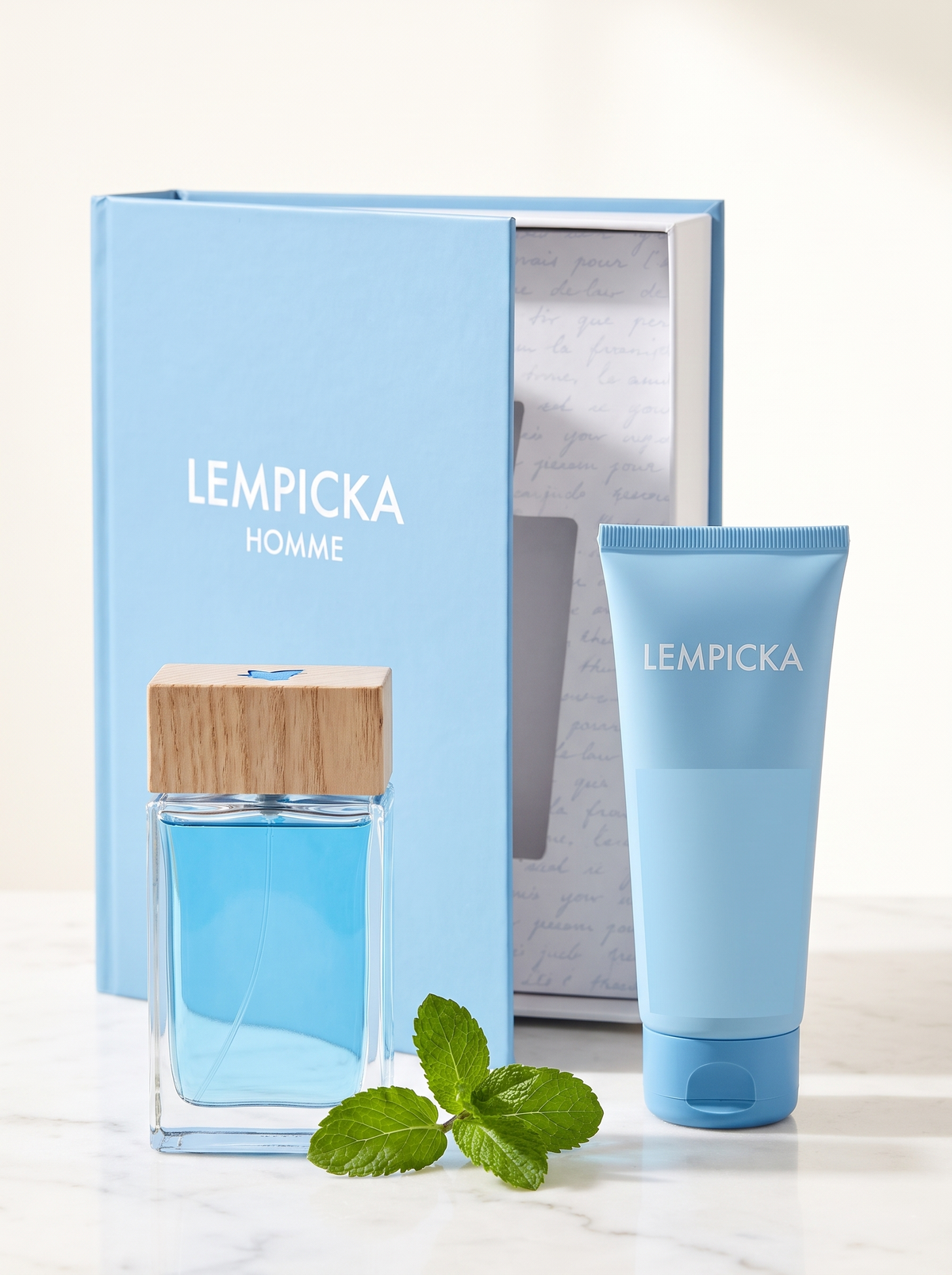 Lolita Lempicka Homme Eau de Toilette Geschenkset - blauer Flakon mit Duschgel auf weissem Marmor mit Minze