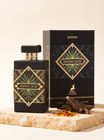Maison Alhambra Joyous Infini Oud Eau de Parfum 100 ml - schwarzer Flakon mit Verpackung auf Sandstein mit Oudholz und Safran