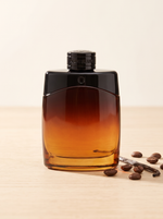 Montblanc Legend Night Eau de Parfum 100 ml - bernsteinfarbener Flakon auf hellem Holz mit Kaffeebohnen und Vanille
