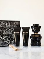 Moschino Toy Boy Geschenkset - schwarzer Baerchen-Flakon mit Duschgel und Bodylotion auf weissem Marmor