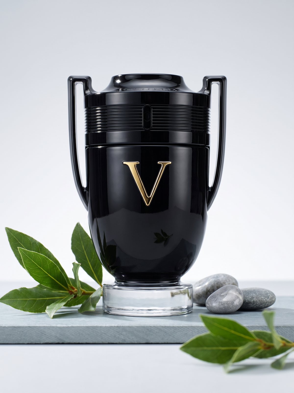 Paco Rabanne Invictus Victory Eau de Parfum Extreme 50 ml - schwarzer Pokal-Flakon auf hellem Schiefer mit Lorbeer