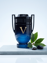 Paco Rabanne Invictus Victory Elixir Eau de Parfum 50 ml - Pokal-Flakon auf hellem Schiefer mit Lorbeer