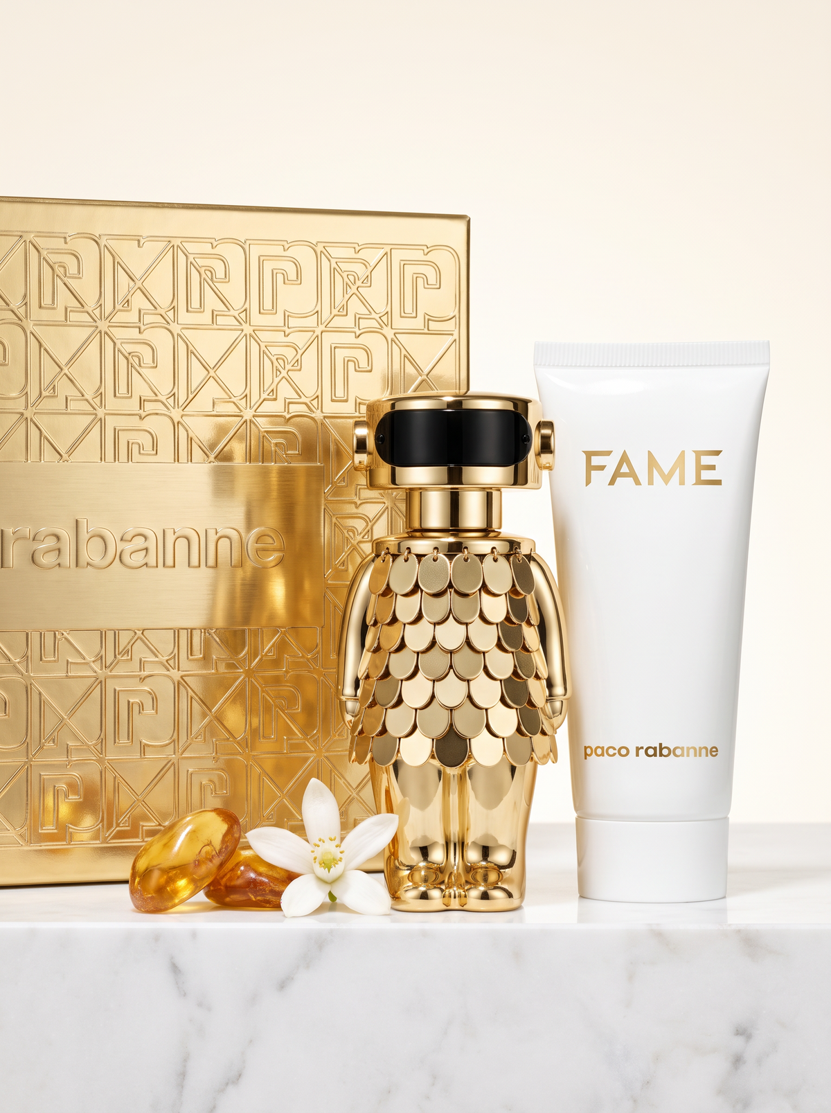 Paco Rabanne Fame Intense Geschenkset - goldener Figur-Flakon mit Bodylotion und Verpackung auf hellem Marmor