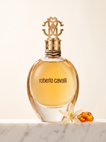Roberto Cavalli Eau de Parfum 50 ml - goldener Flakon auf weissem Marmor mit Orangenbluete und Bernstein