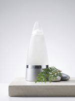 Rochas Man Eau de Toilette 100 ml - weisser Kegelflakon auf hellem Beton mit Zedernzweig