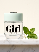 Rochas Girl Eau de Toilette 75 ml - klarer Flakon mit mintgruener Kappe auf weissem Marmor mit Minze