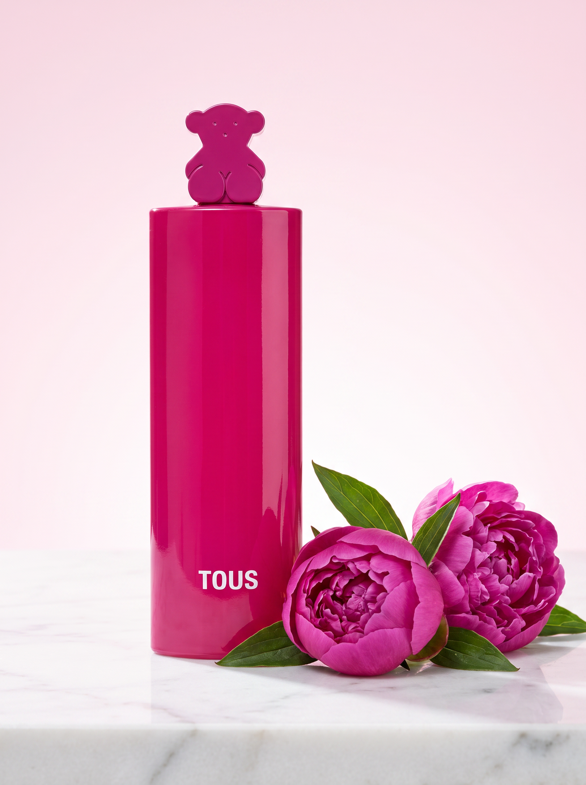 Tous More More Pink Eau de Toilette 50 ml - pinker Flakon mit Baerchen-Verschluss auf hellem Marmor mit Pfingstrosen