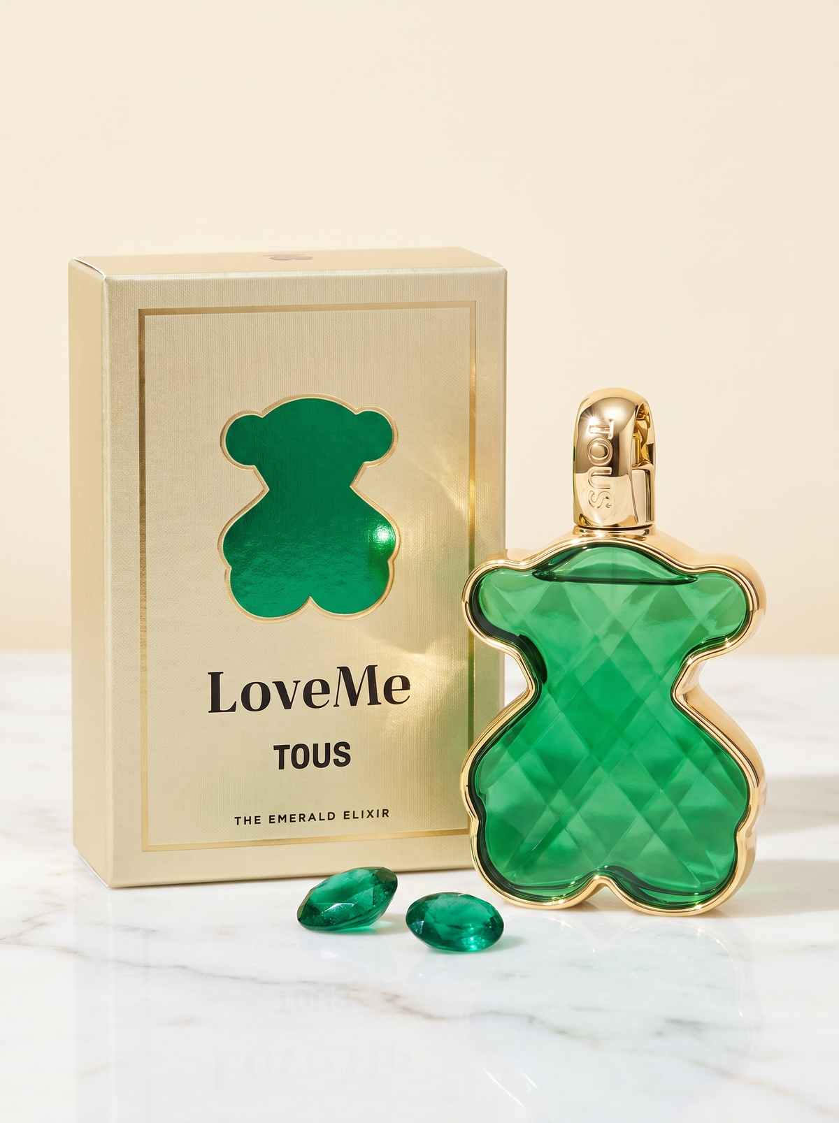 Tous LoveMe The Emerald Elixir Eau de Parfum 50 ml - gruener Baerchen-Flakon mit Verpackung auf weissem Marmor