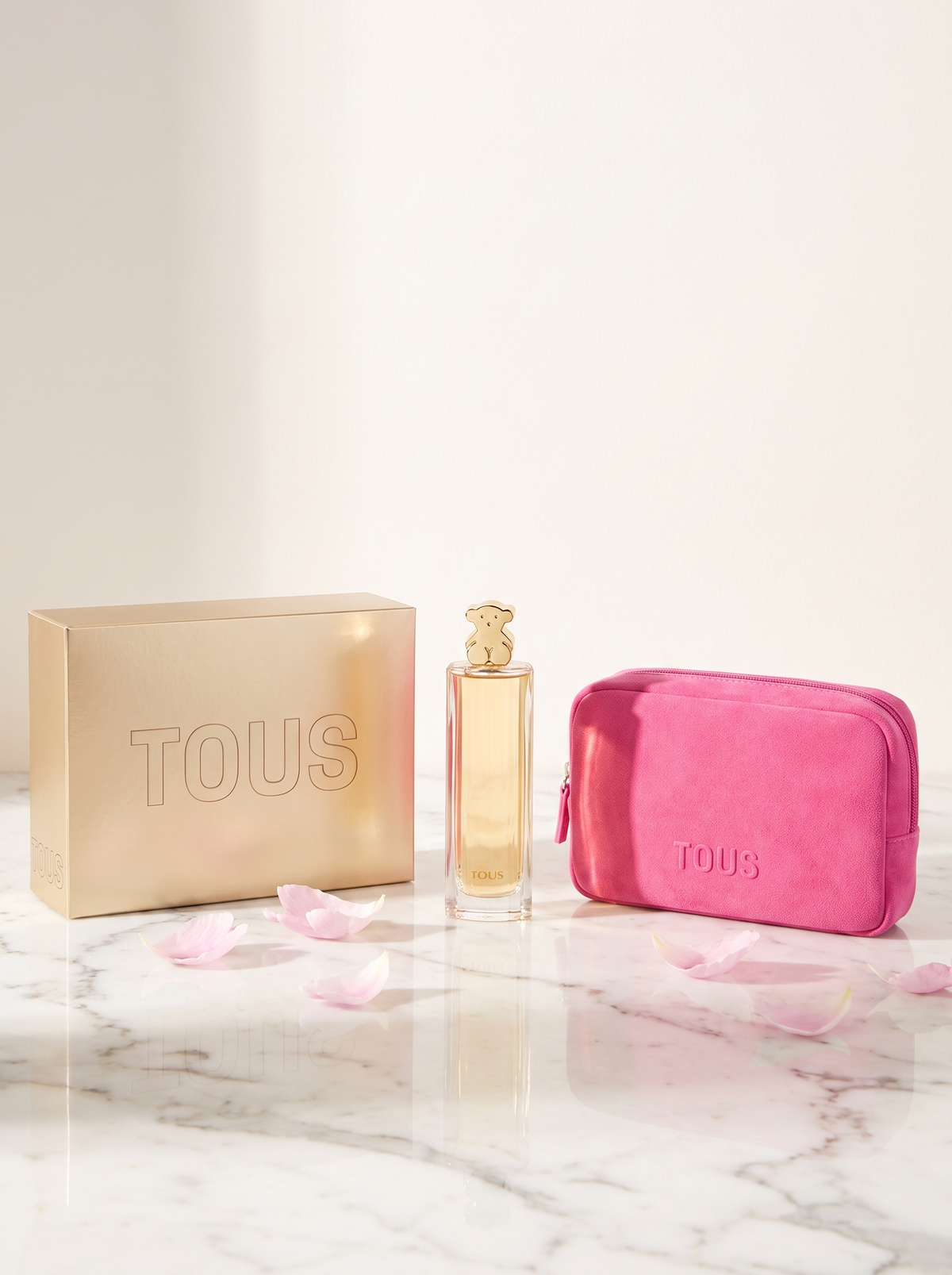 Tous Eau de Parfum 90 ml Set mit Kosmetiktasche auf weissem Marmor mit Pfingstrosenblaettern