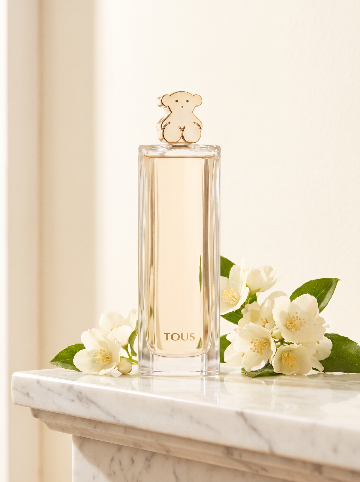 Tous Eau de Parfum 50 ml - Flakon mit goldenem Baerchen auf weissem Marmor mit Jasmin