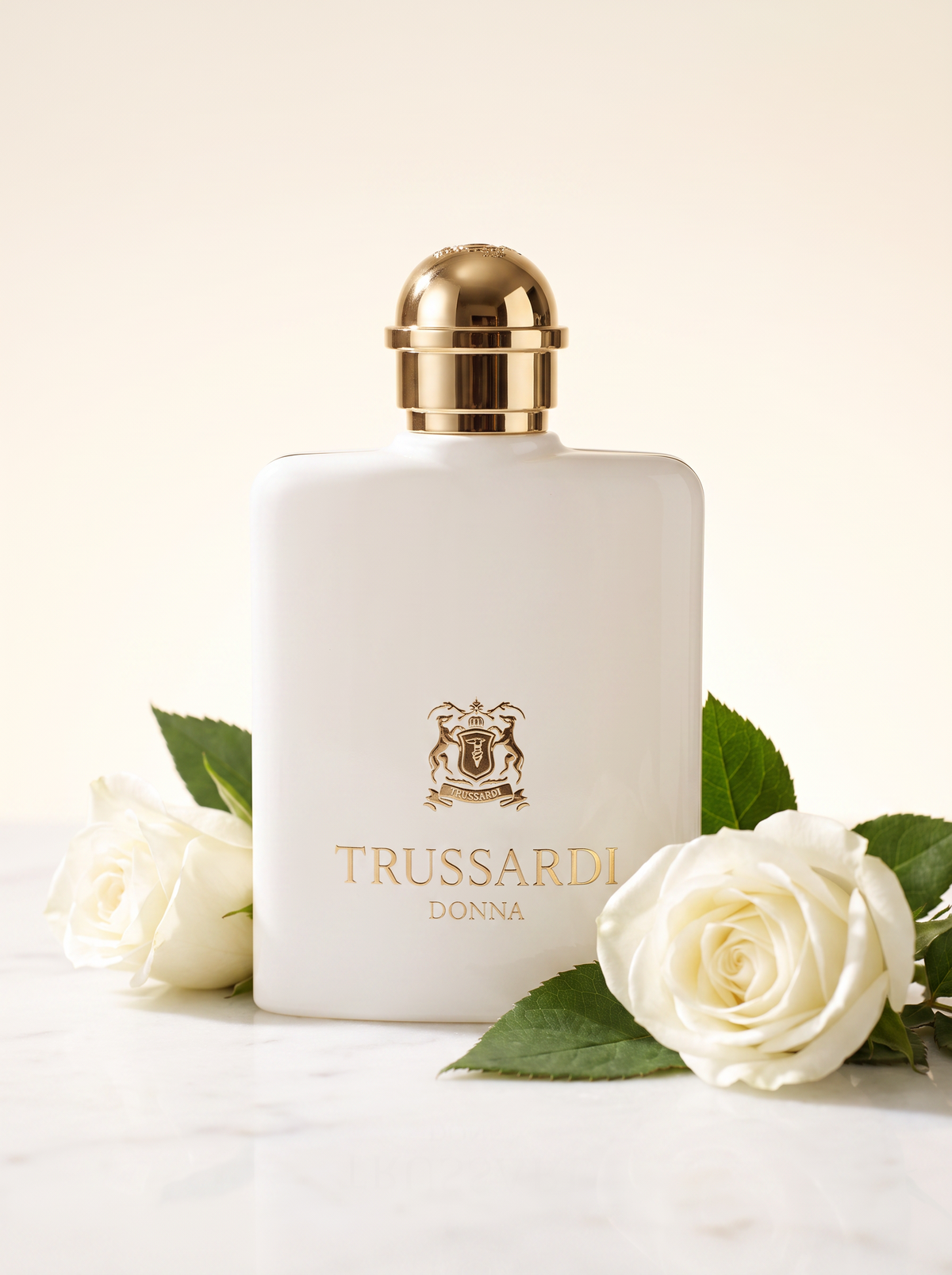 Trussardi Donna Eau de Parfum 100 ml - weisser Flakon mit Goldkappe auf hellem Marmor mit weissen Rosen