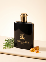 Trussardi Uomo Eau de Toilette 200 ml - schwarzer Flakon mit Goldwappen auf hellem Leder mit Zeder und Bernstein